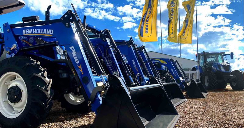 Line up of new holland tractors close up with flags flying in the sky